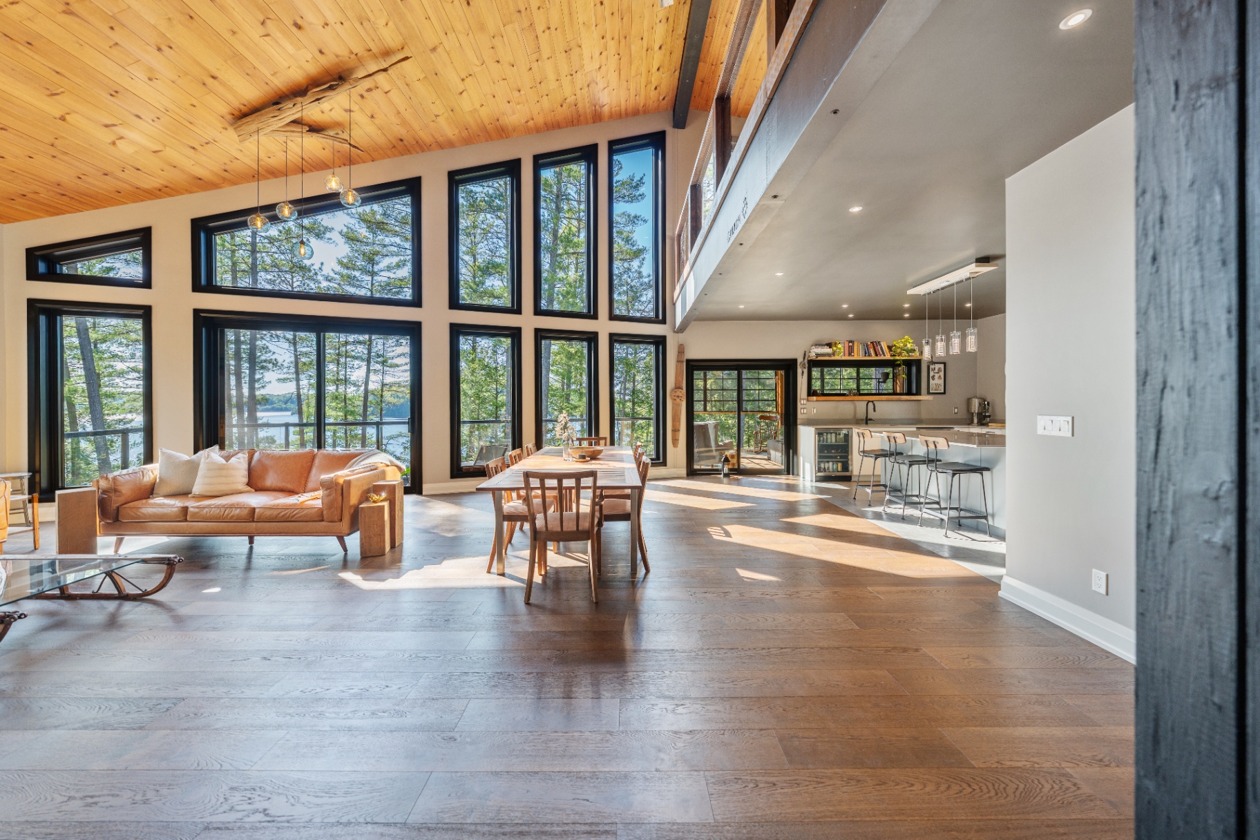 Great room with leather sofa, dining table, and lake-facing wall of windows