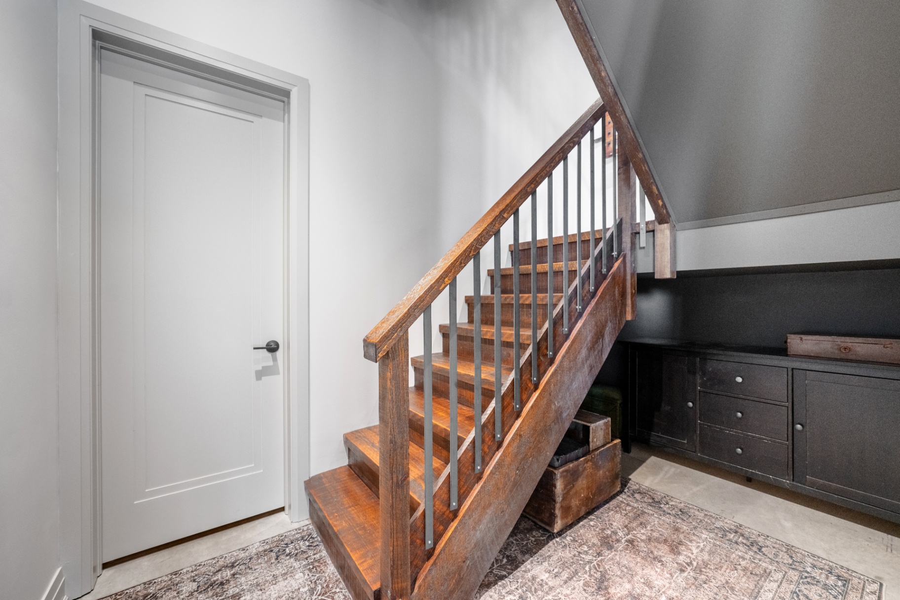 Lower-level landing with reclaimed timber staircase and storage nook