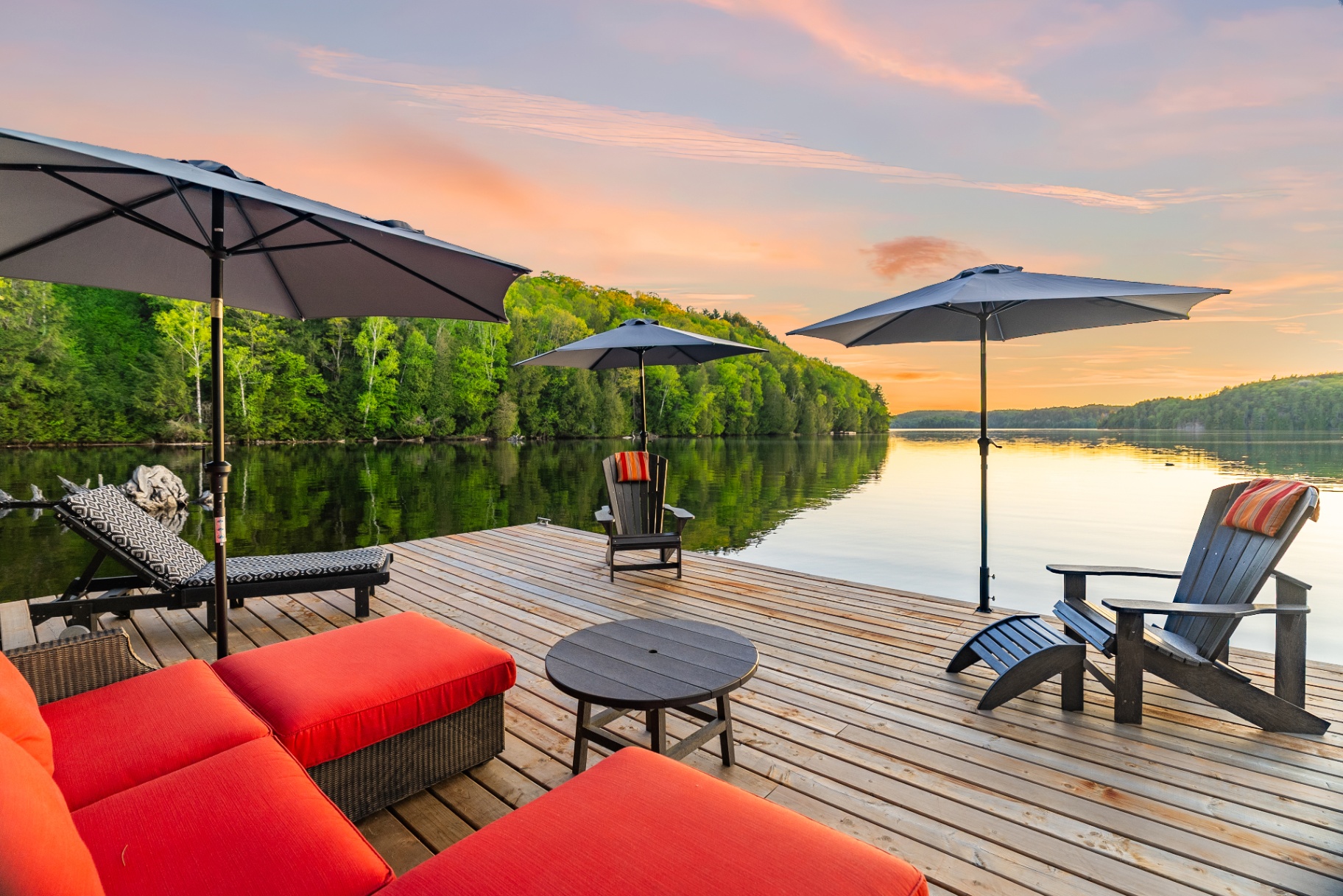 Wide sunset panorama from the dock with red lounge seating and three umbrellas