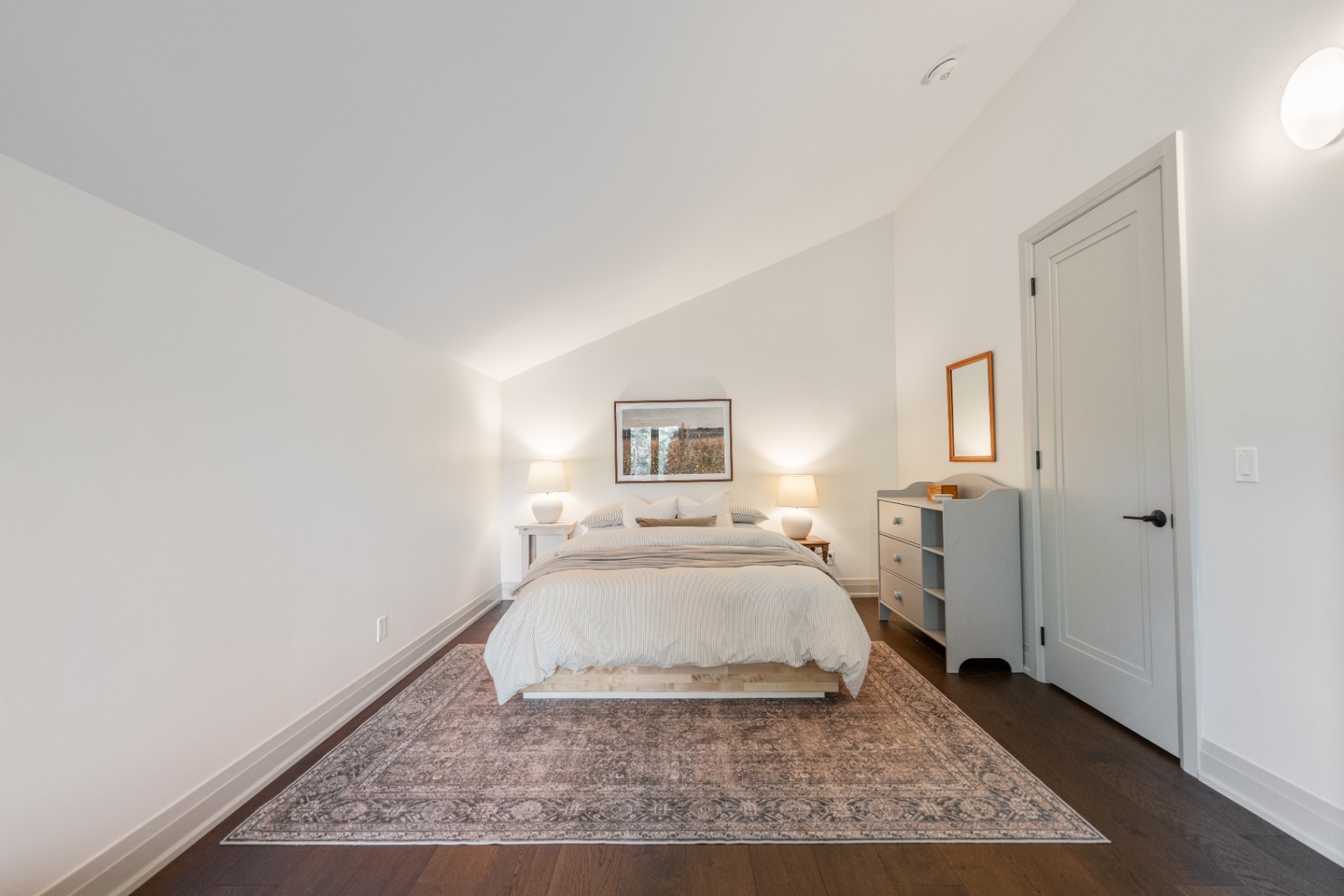 Upper bedroom with centered bed and soft neutral styling