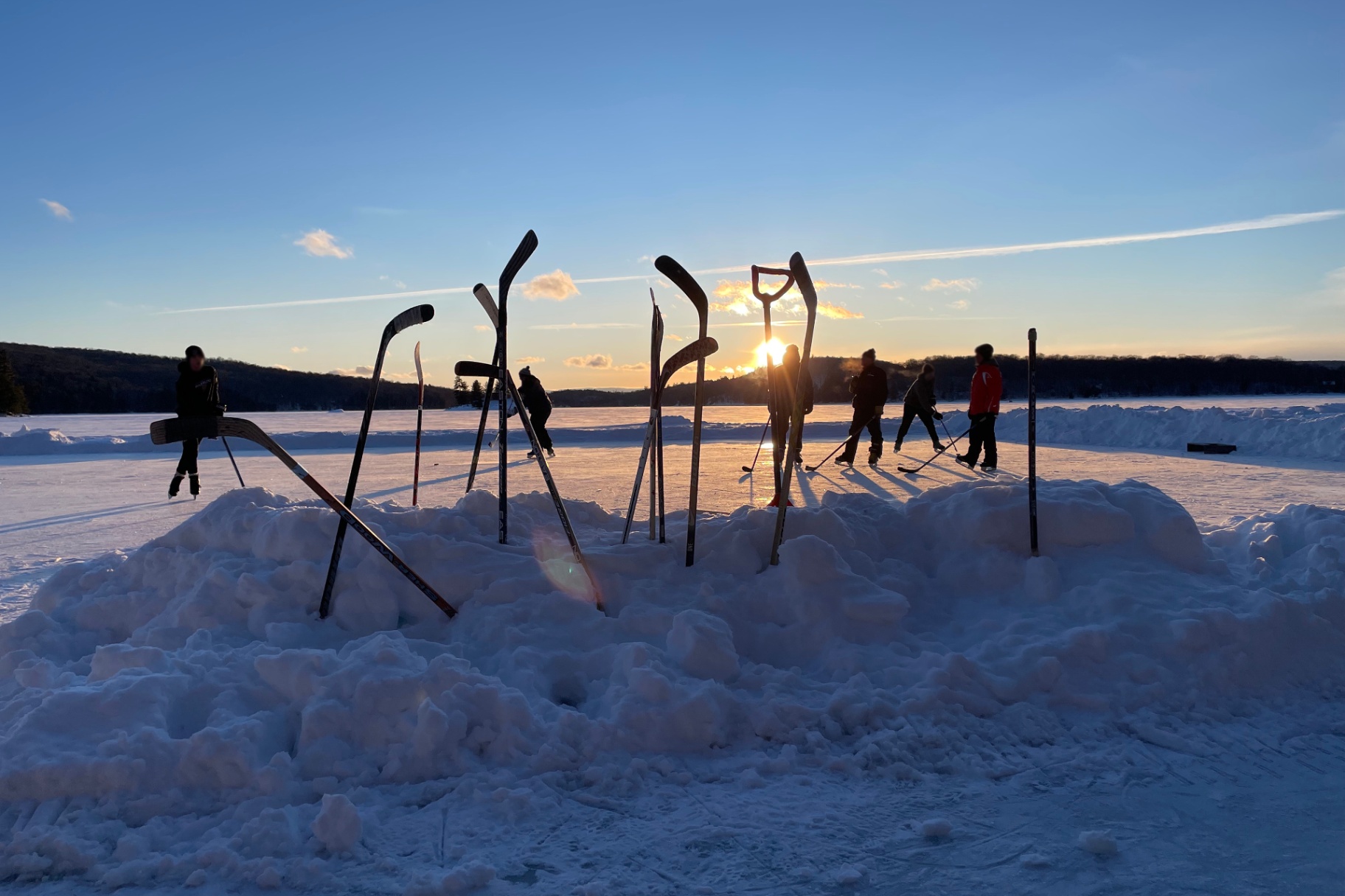 Pond hockey on frozen Redstone Lake at sunset with sticks planted in snowbanks