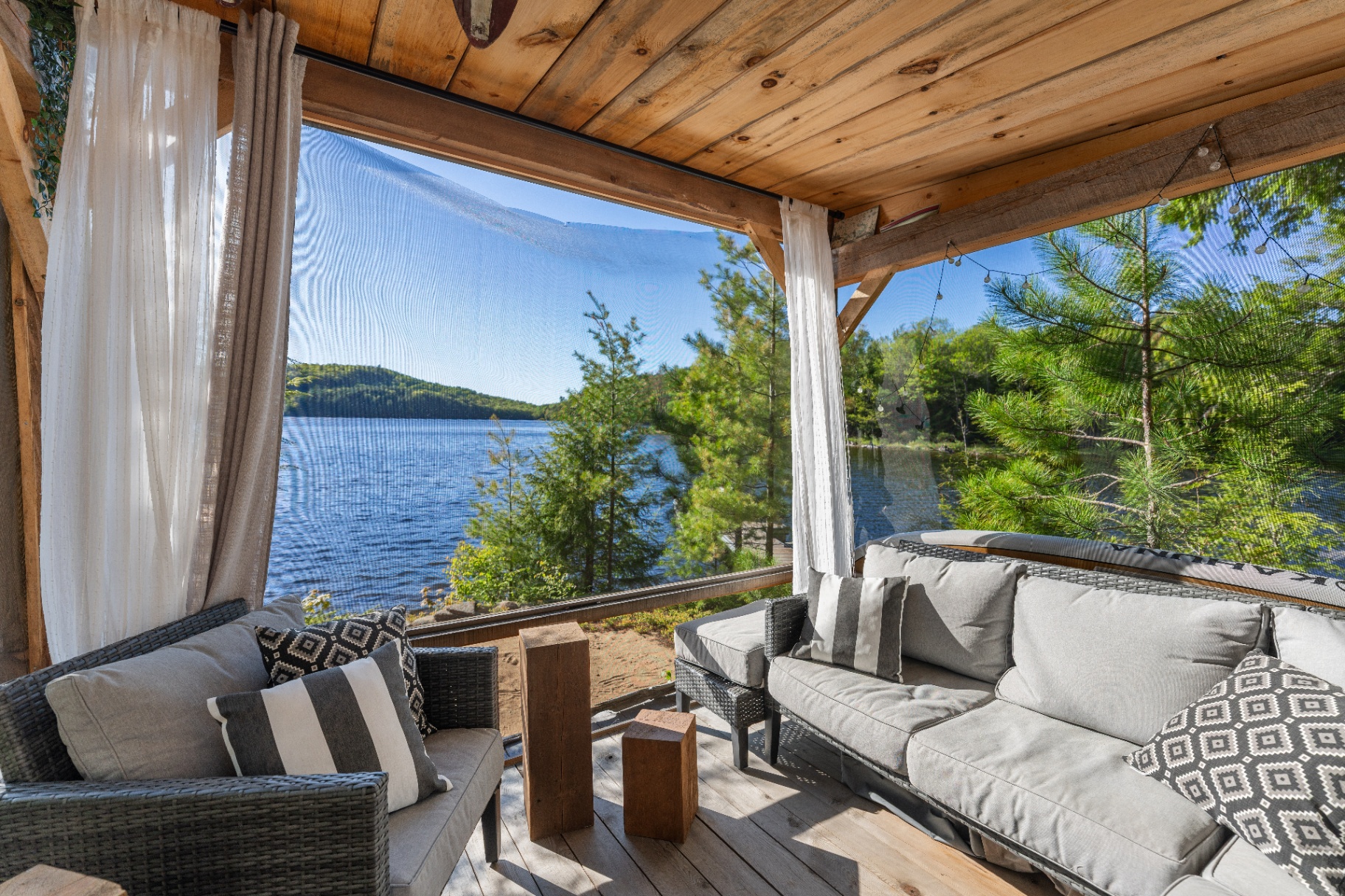 Screened lakeside lounge with wicker seating and panoramic water view