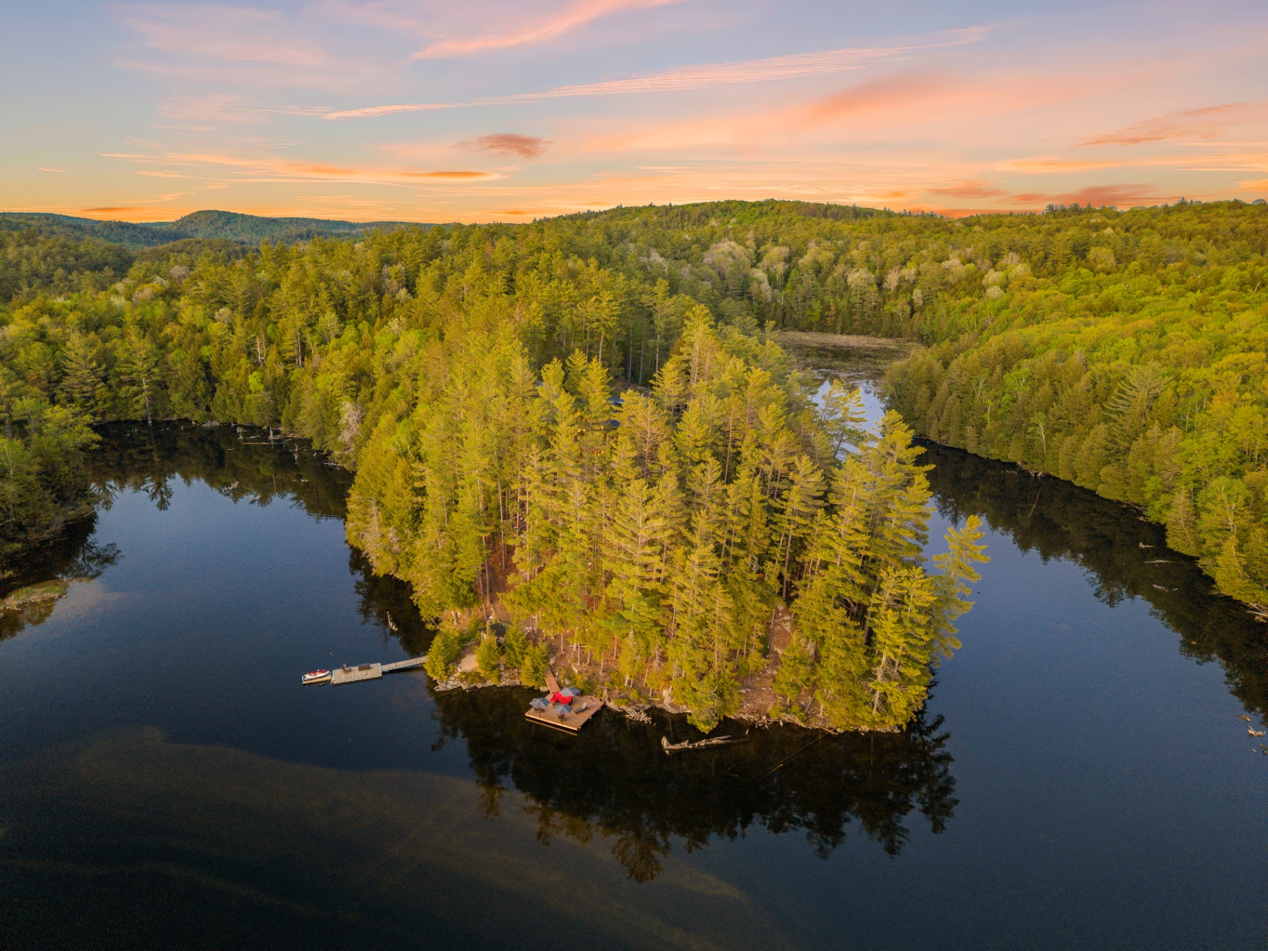 Aerial of the private peninsula with dock and floating lounge platform in calm evening light