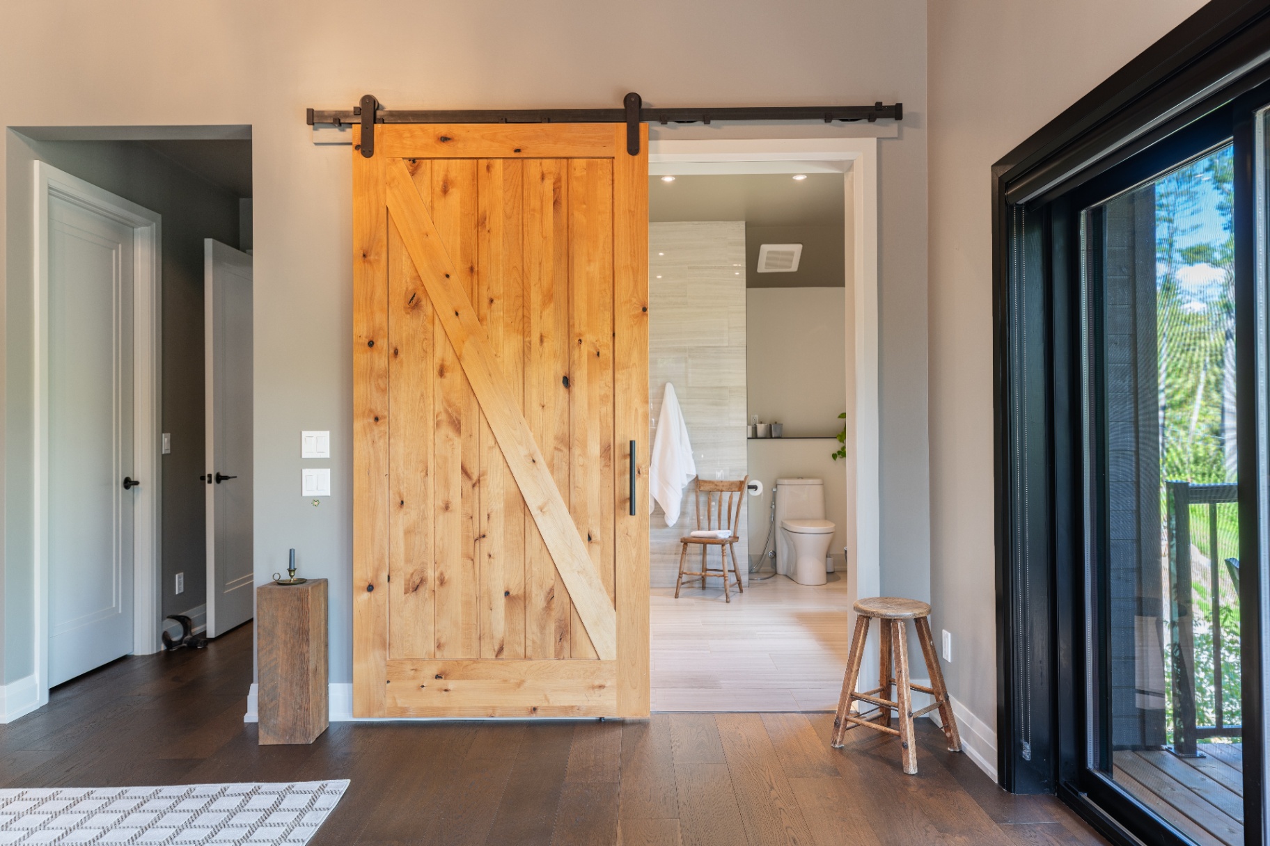 Primary suite barn door leading toward the ensuite bath
