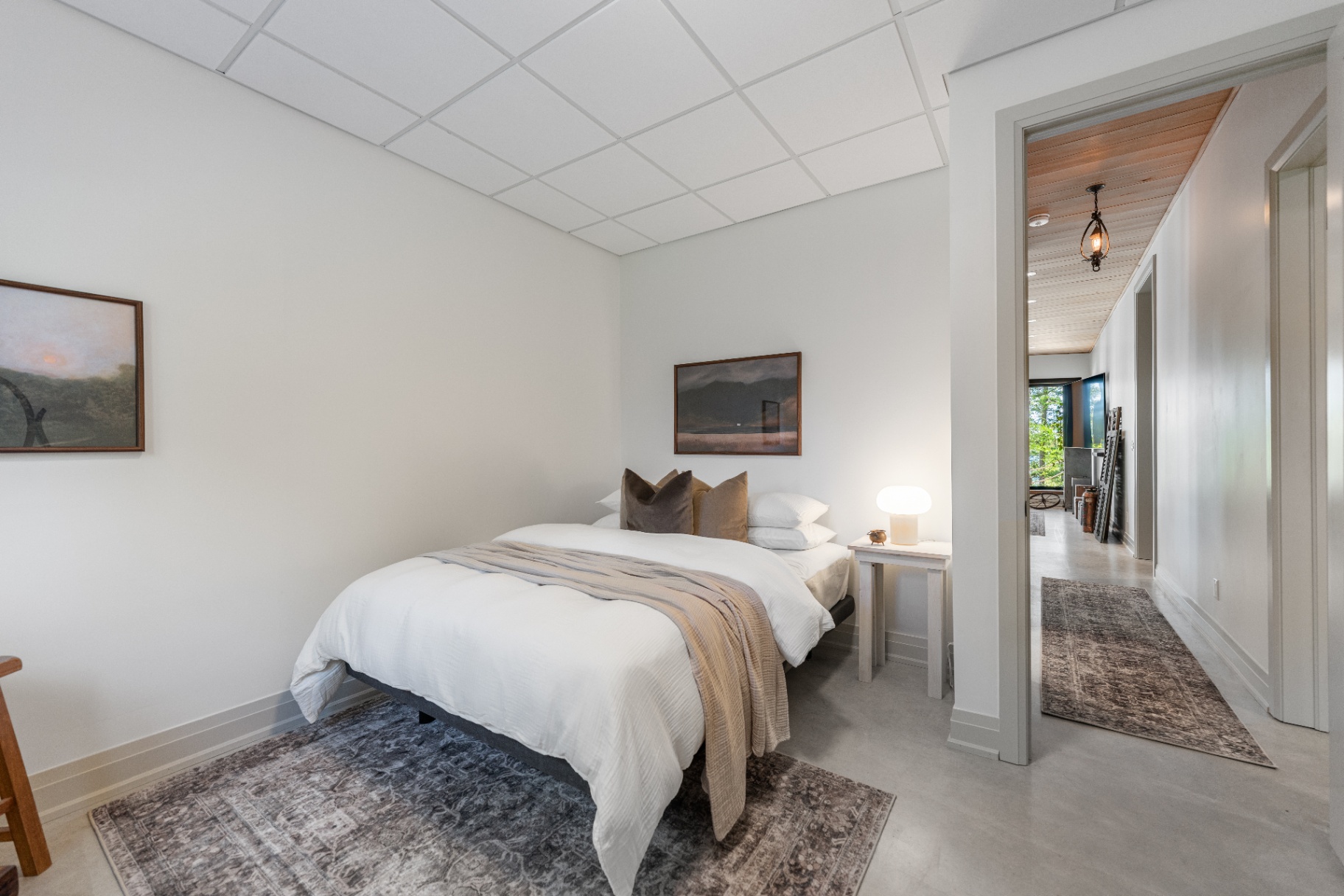Lower-level bedroom with hallway view and neutral bedding