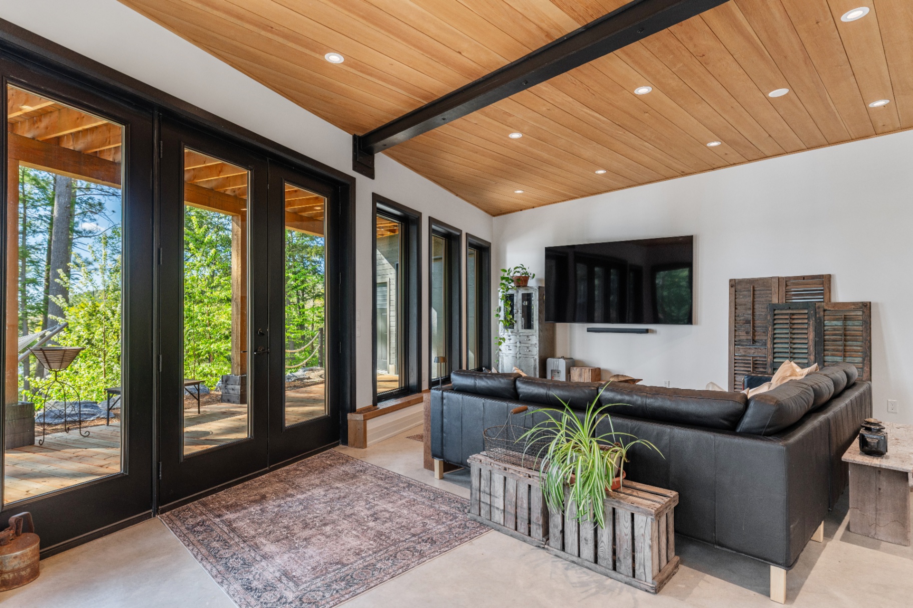 Walkout lounge with media wall and double doors to the deck