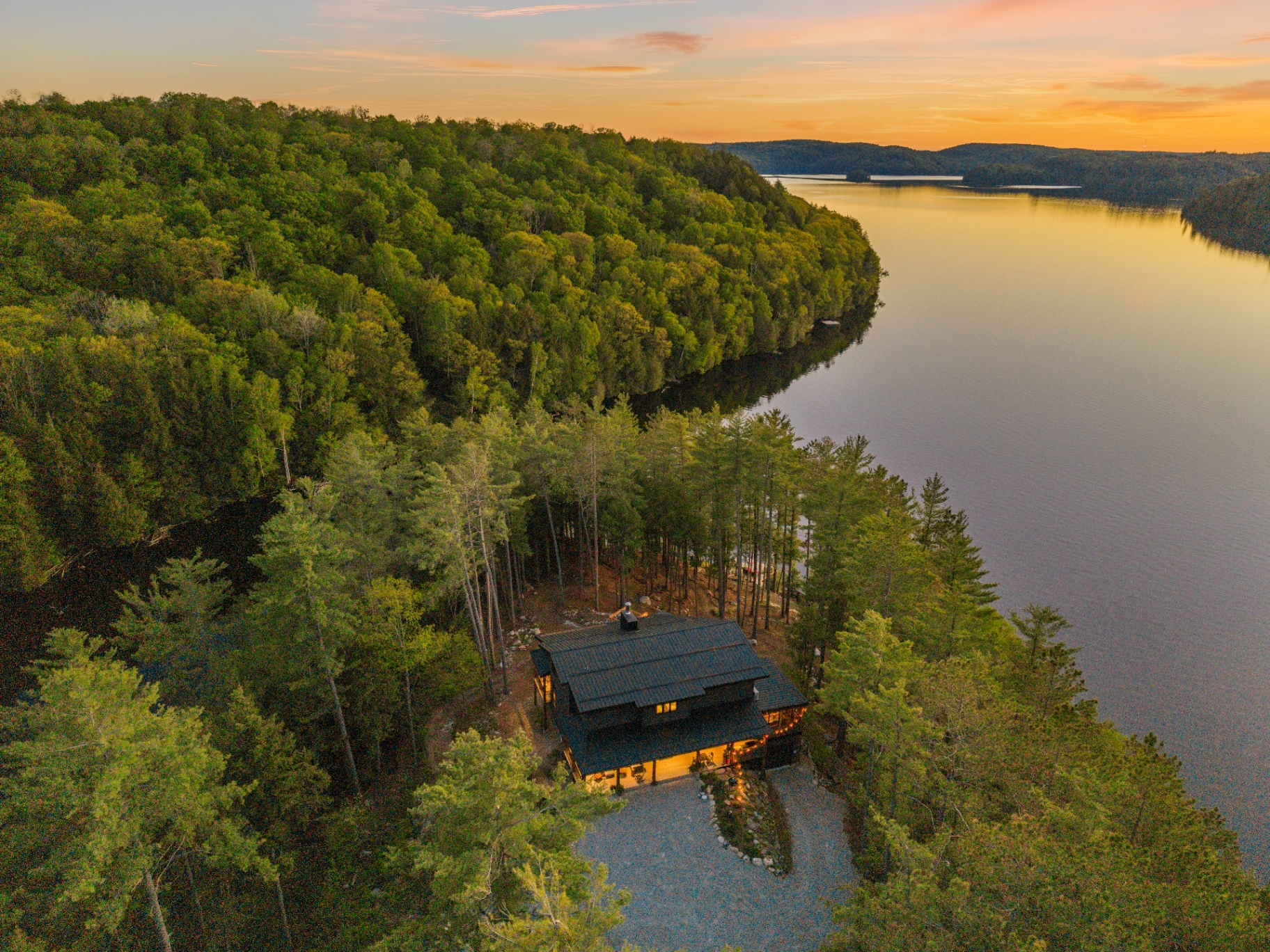 High aerial of the peninsula home tucked beside open lake and wetland channel at sunset