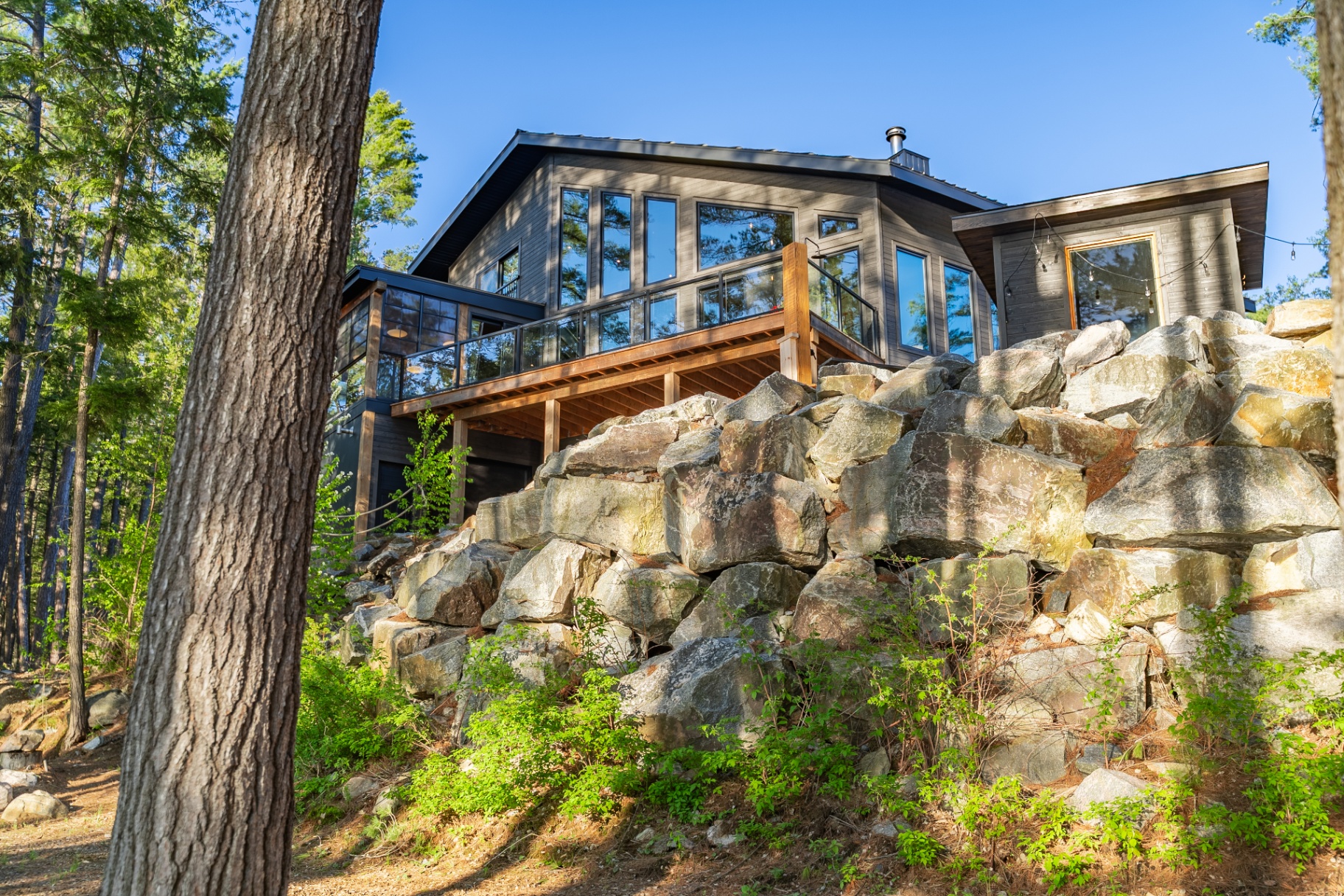 Dramatic rear elevation rising above the granite outcrop and deck