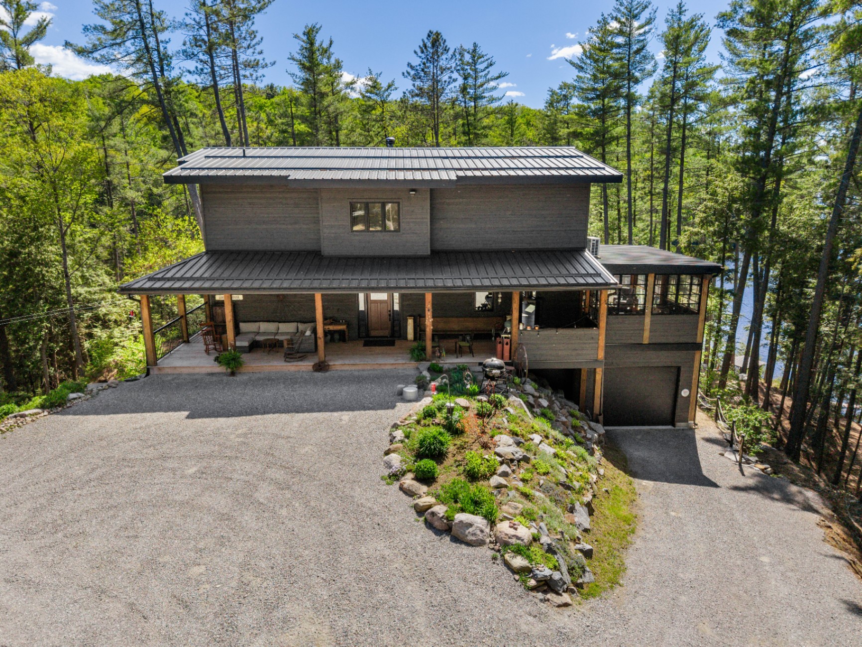 Centered drone view of the front approach with landscaped granite island