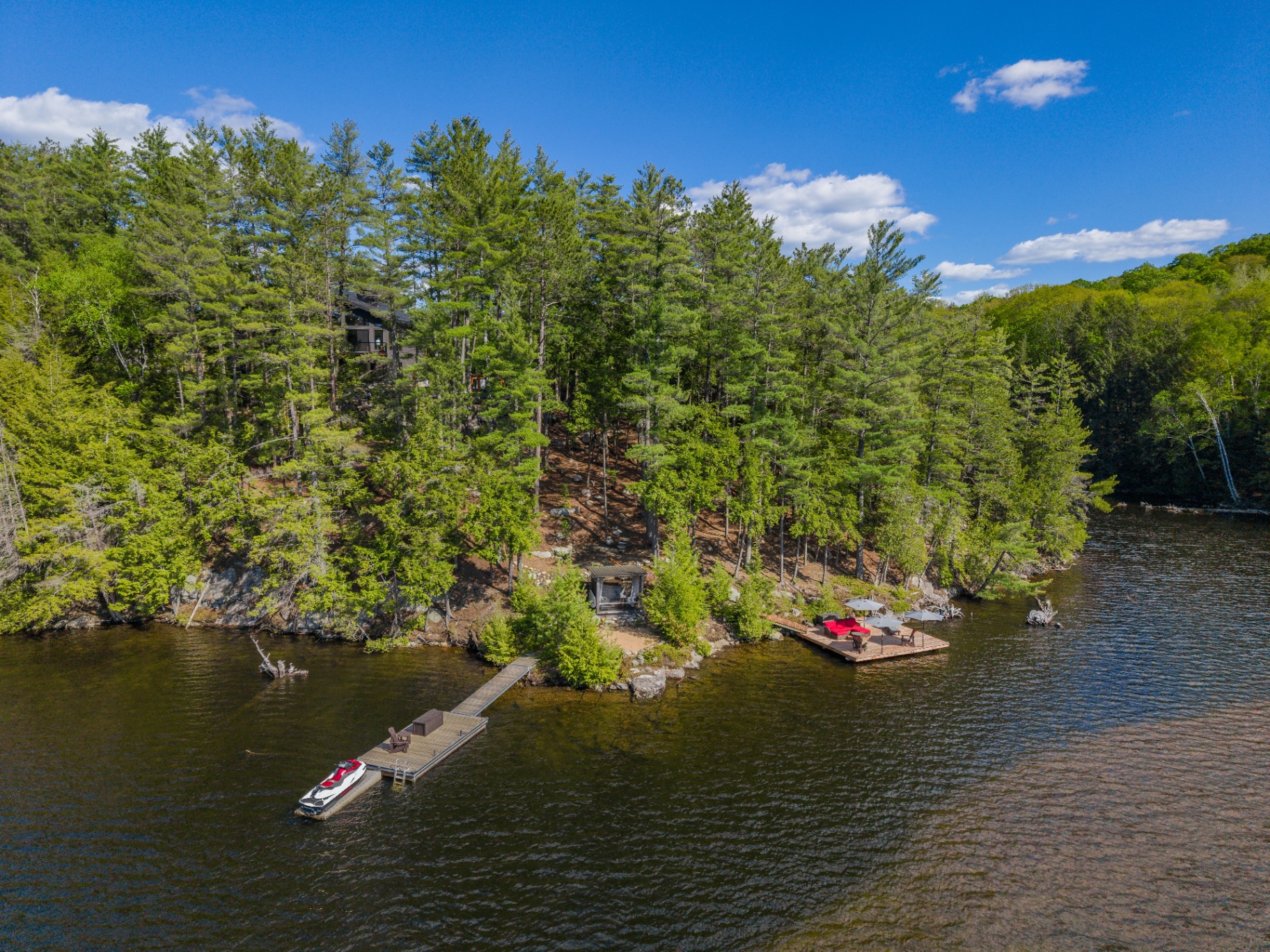 Broader lakeside elevation showing the home perched privately along the rocky shoreline