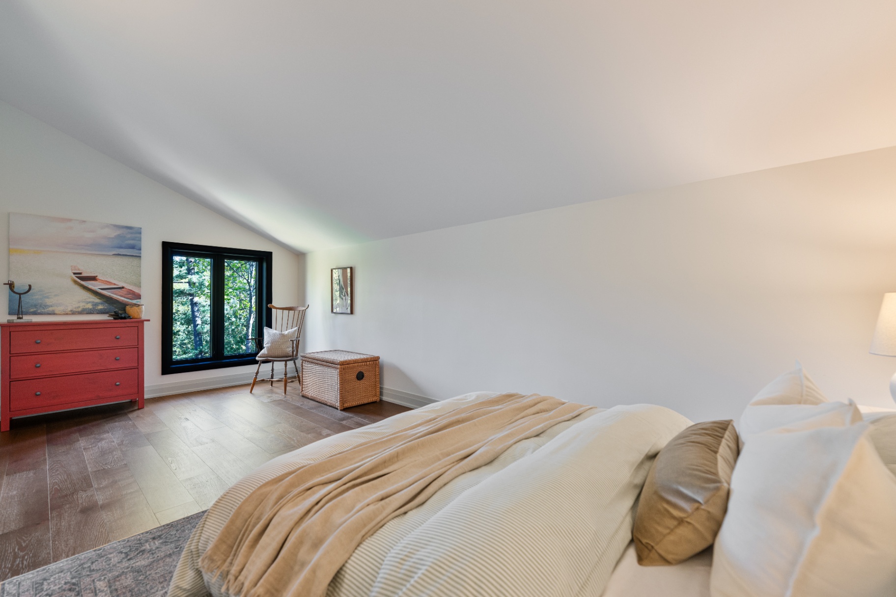 Upper bedroom with lake-inspired artwork and reading chair by the window