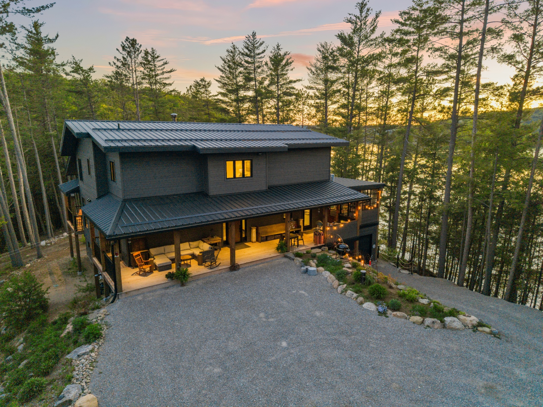 Aerial front view at twilight showing the broad porch and curved gravel approach