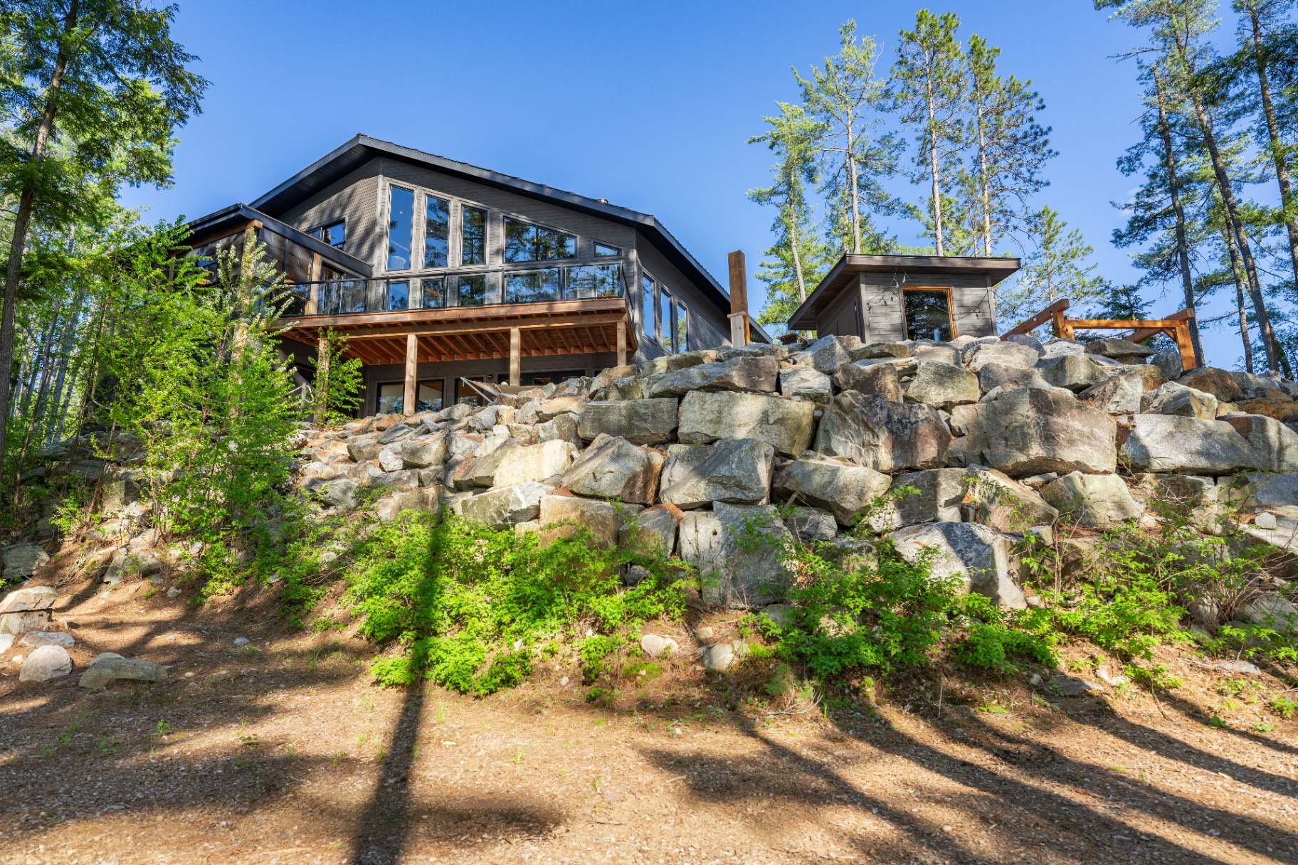 Lake house and sauna rising above the granite rock wall