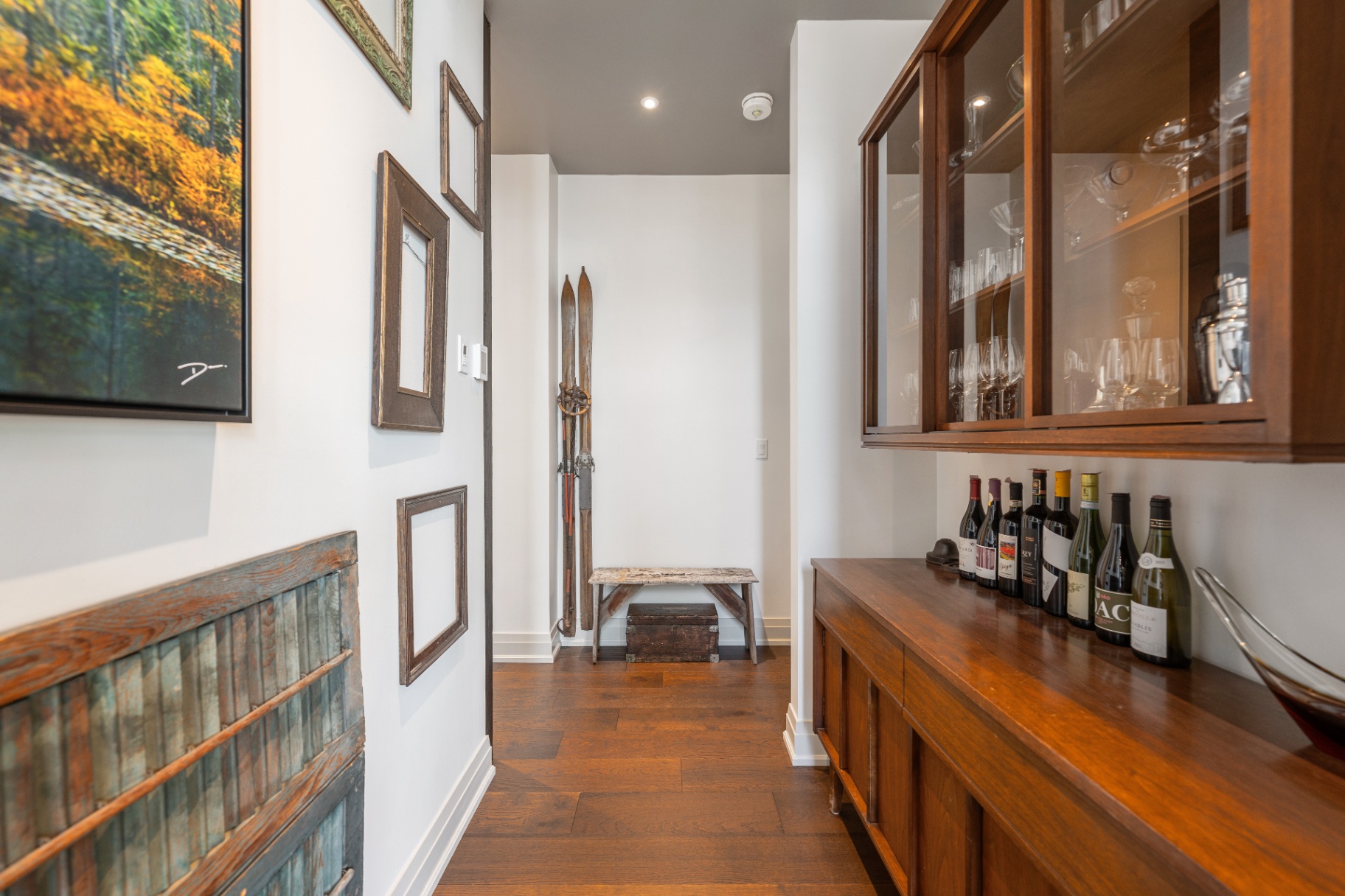 Hallway bar area with vintage skis and glass cabinetry