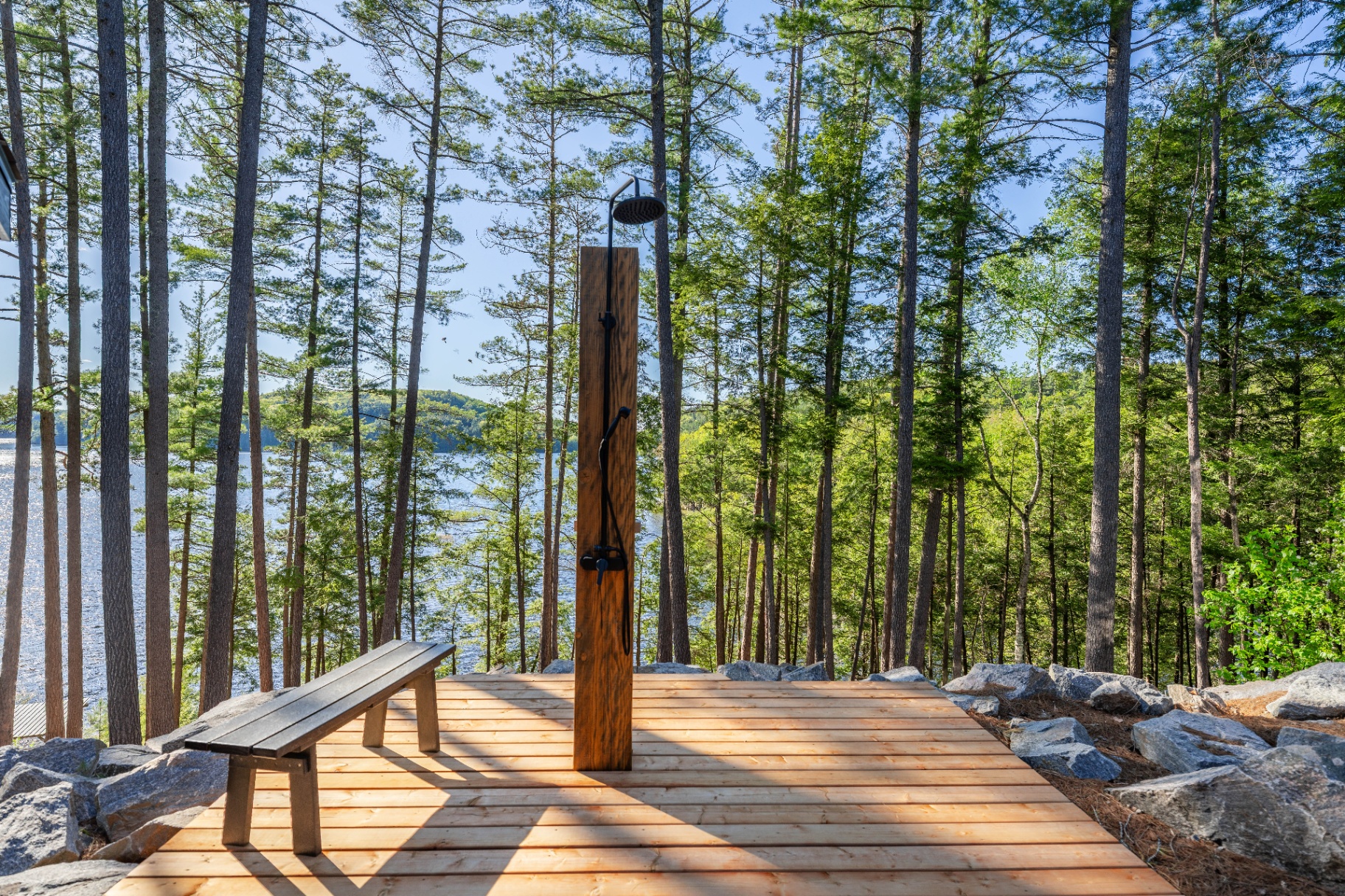 Outdoor shower platform with lake and pine forest backdrop