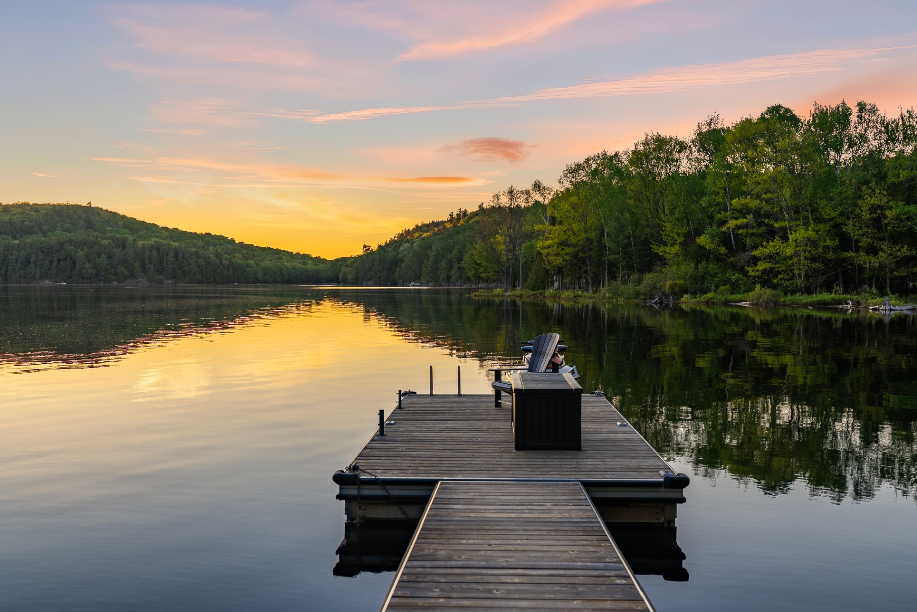 Long view down the dock toward a golden sunset reflected on calm water