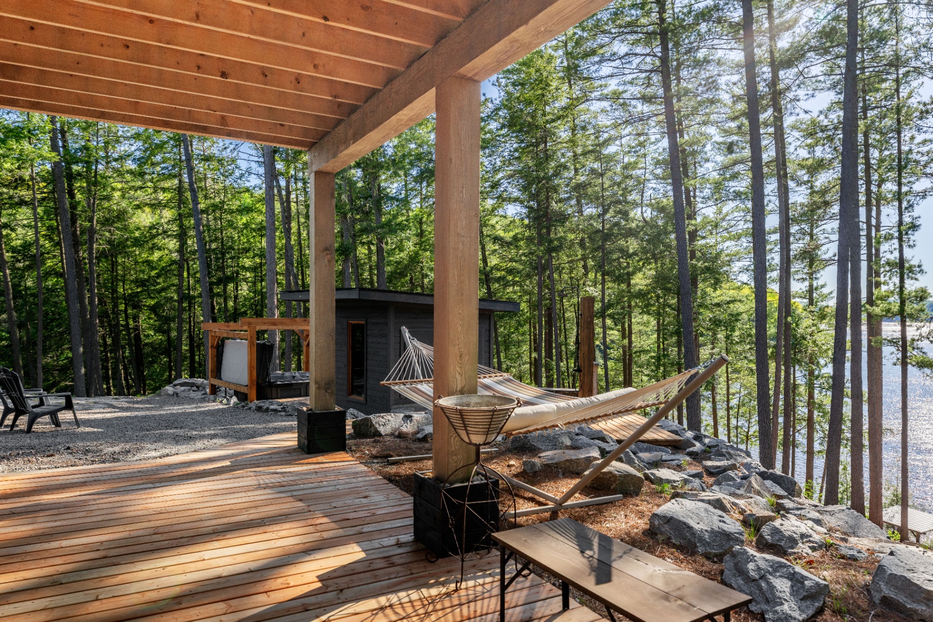 Lakeside deck lounge with hammock, hot tub, and treetop water view