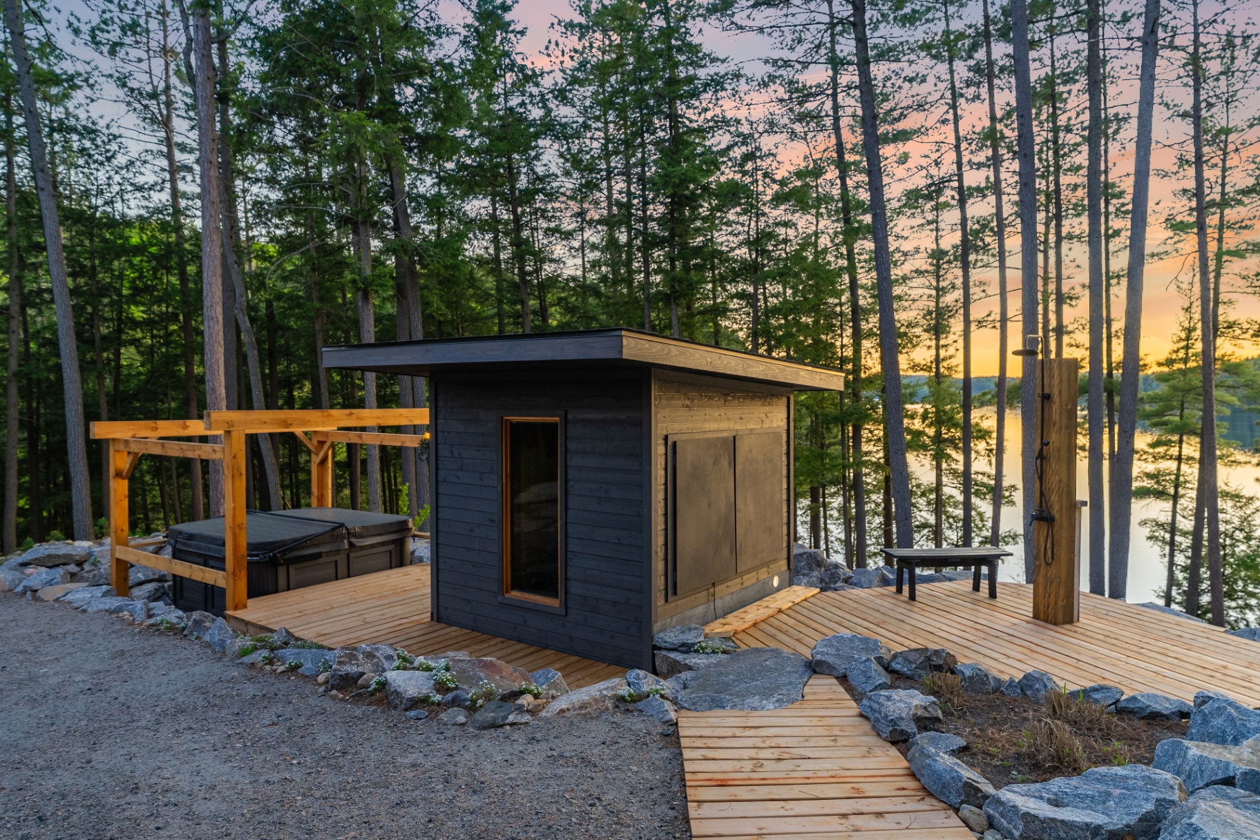 Outdoor shower and sauna deck with boardwalk path overlooking the water at dusk