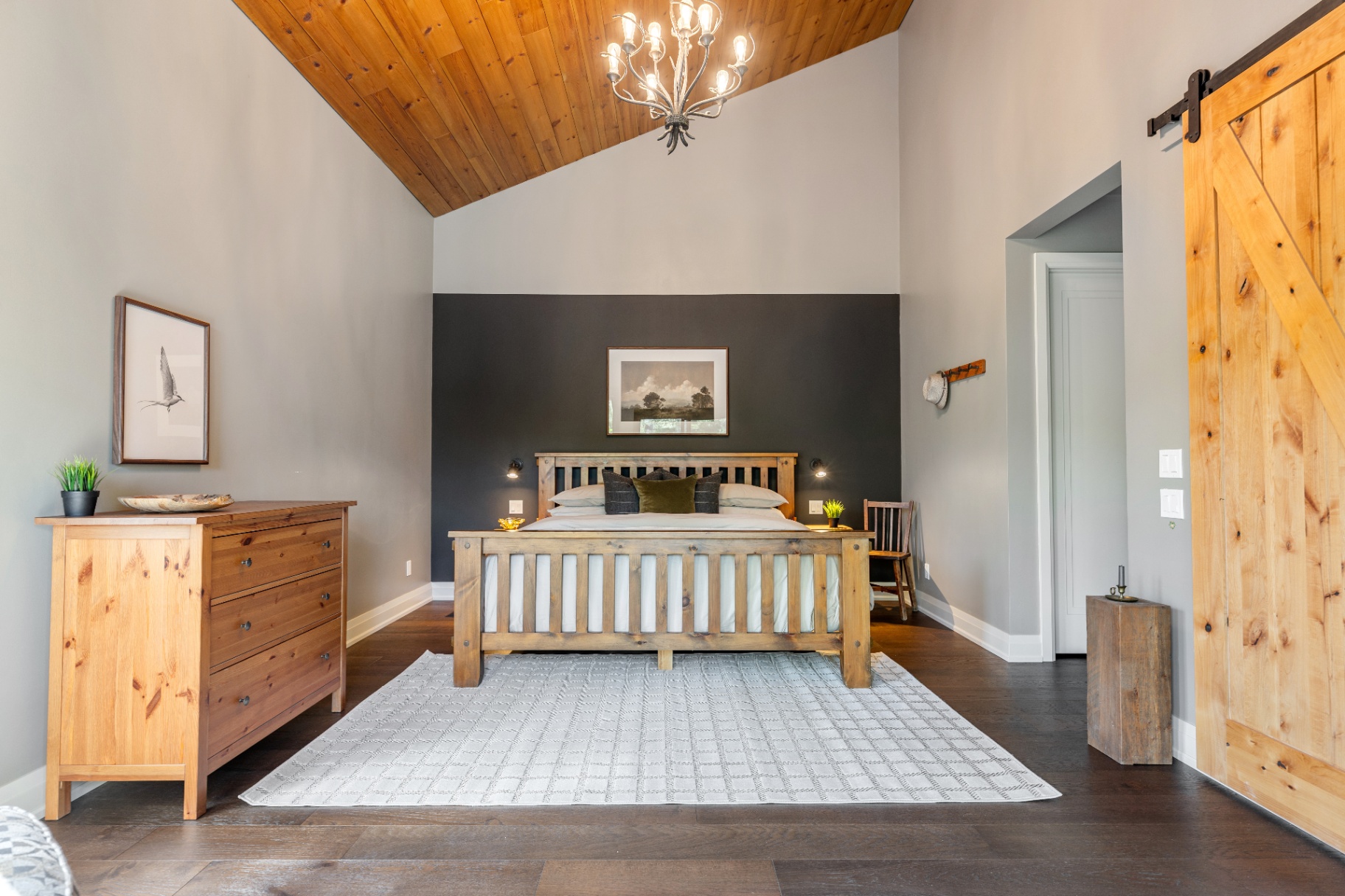 Primary bedroom centered beneath vaulted pine ceiling