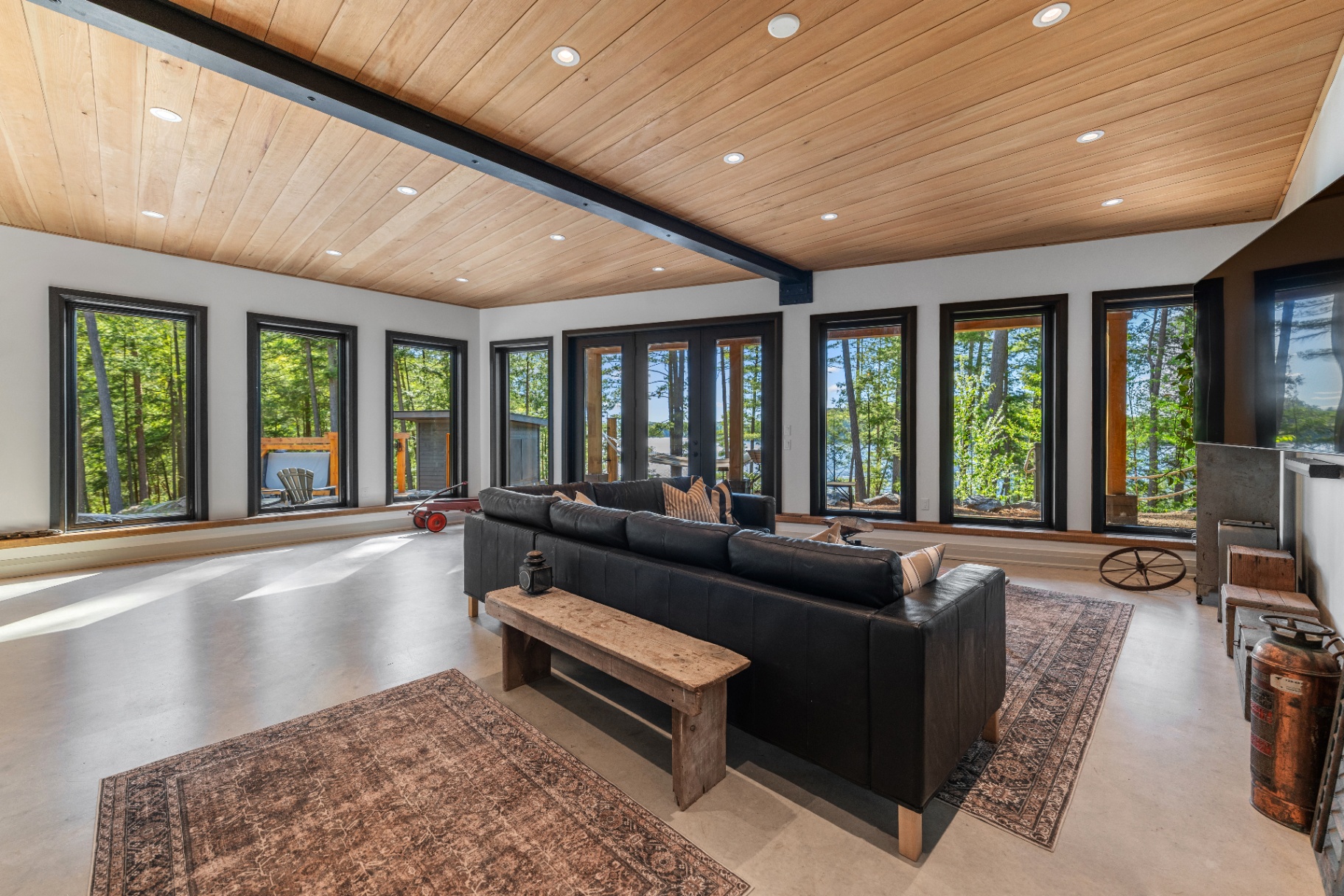 Lower-level family room with wall of windows and wood plank ceiling
