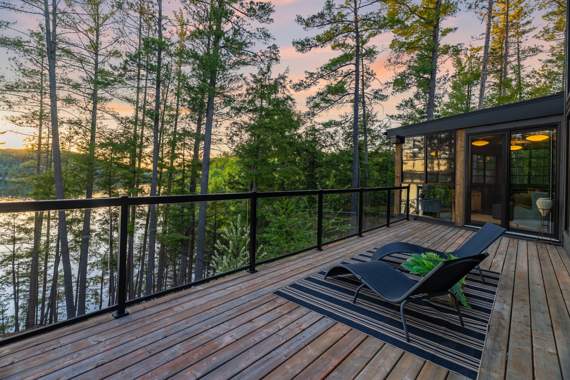 Upper deck at sunset with twin chaise loungers and pink sky over the pines