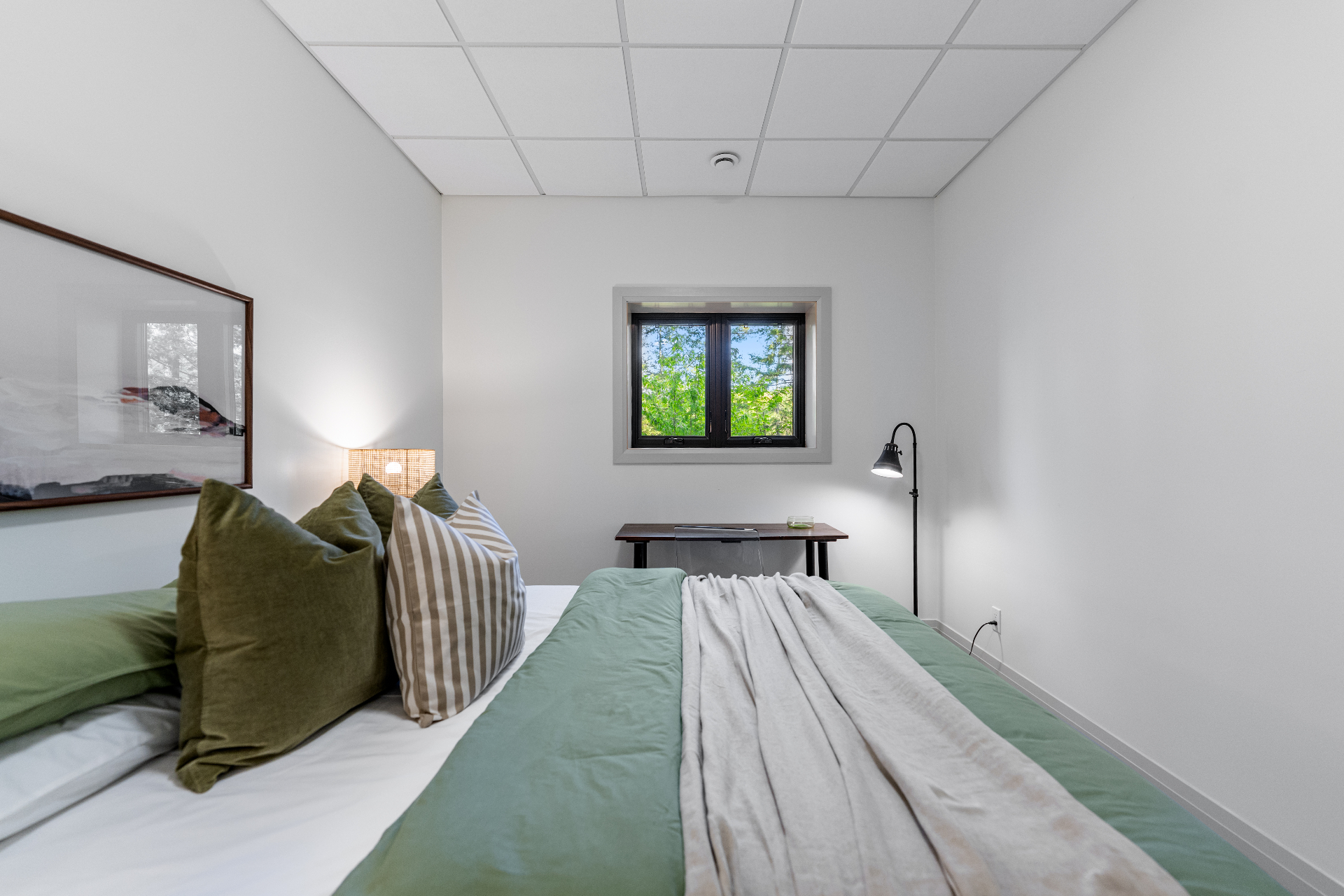 Close bedroom view with layered green linens and workspace