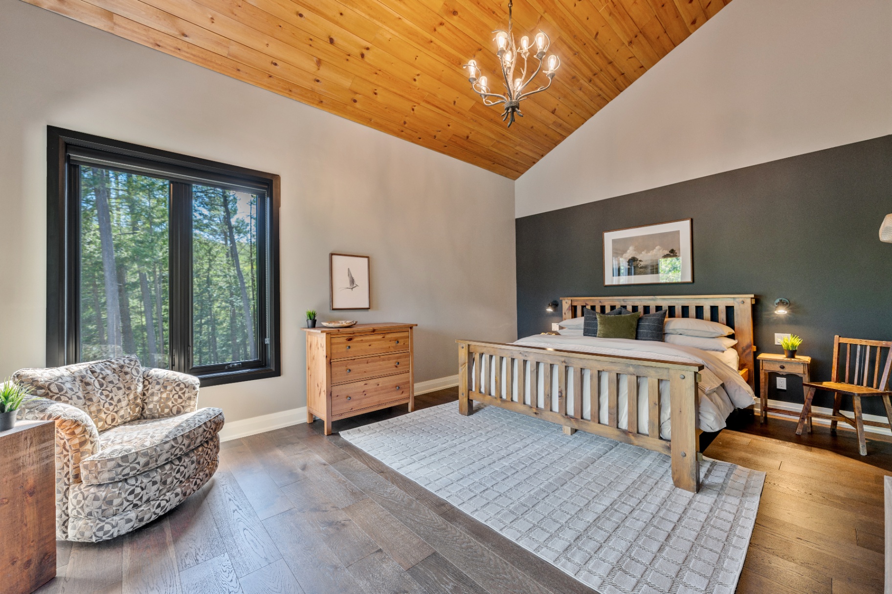 Primary bedroom with wood bed frame and accent wall