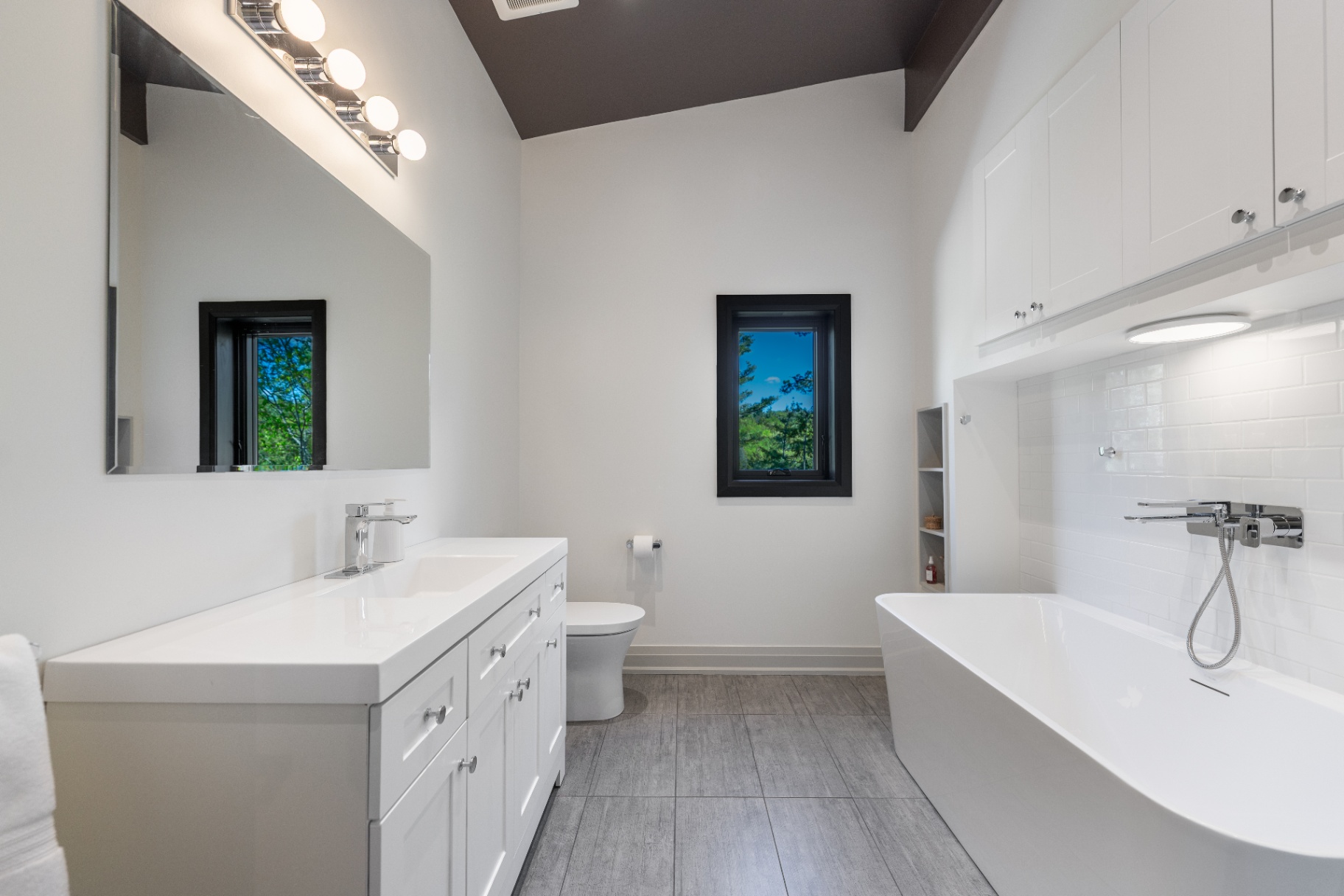Primary bathroom with double vanity, soaking tub, and tall ceiling